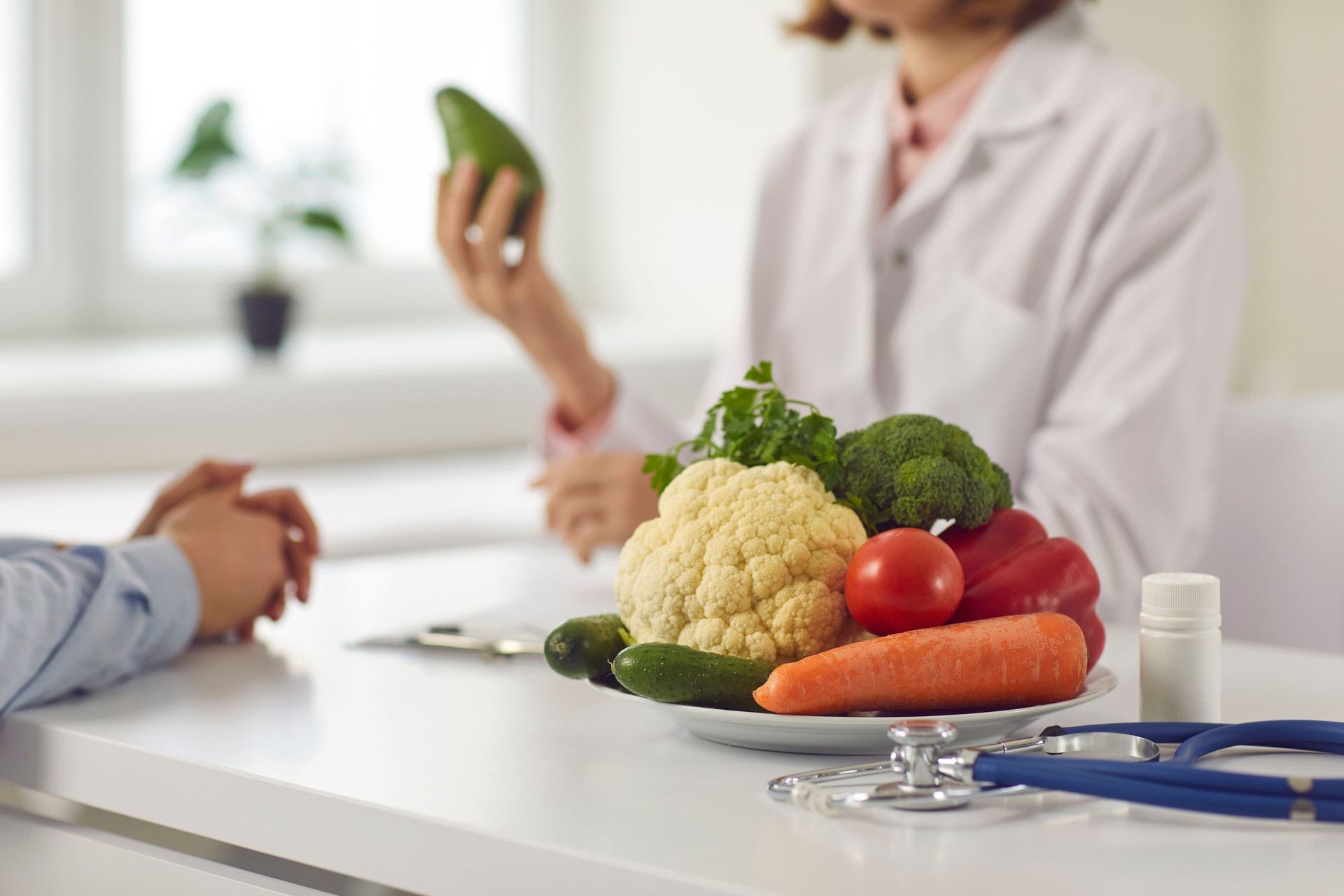 Close up of a plate with vegetables on the background of a nutritionist who provides consultation.
